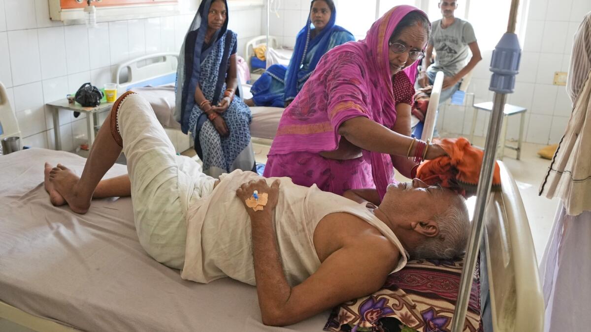 A woman wipes the head of her ailing husband using a wet cloth at the district hospital in Ballia, Uttar Pradesh state, India, on Monday. Photo: AP
