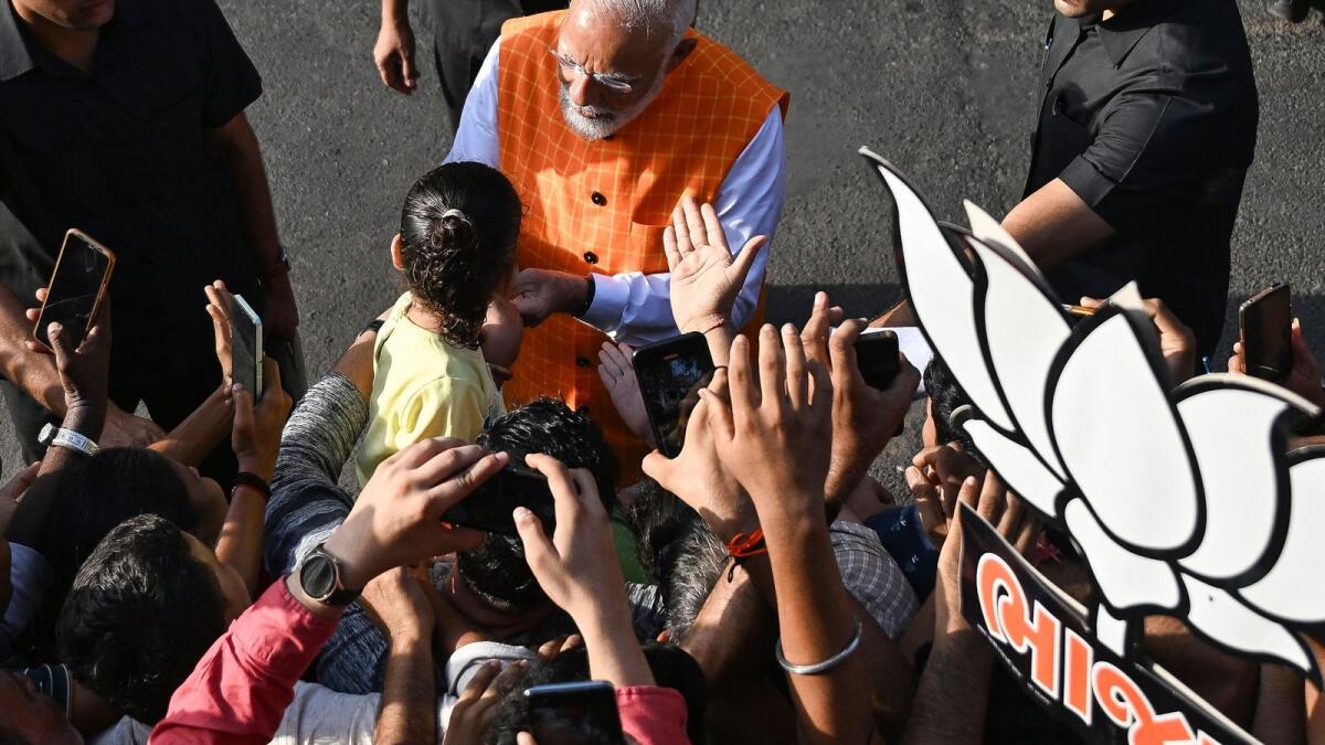 India's Prime Minister Narendra Modi interacts with a young supporter as he leaves after casting his ballot at a polling booth at Ranip, Ahmedabad, on Tuesday. — AFP