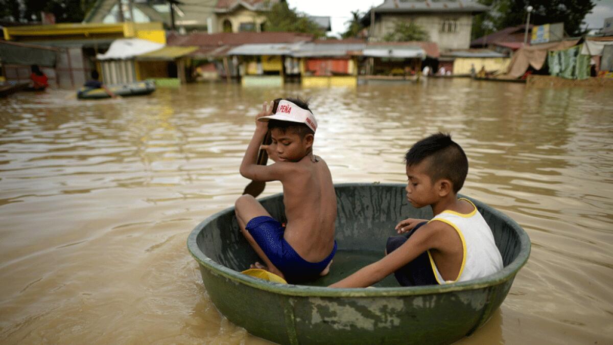 Children commute in a water basin at a flooded market in Candaba, Pampanga, north of Manila.