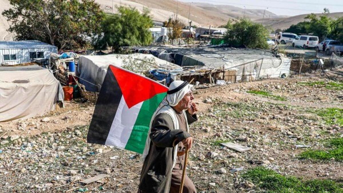 A Bedouin man walks with a Palestinian flag in the village of Khan Al-Ahmar in the Israeli-occupied West Bank on November 29, 2020.