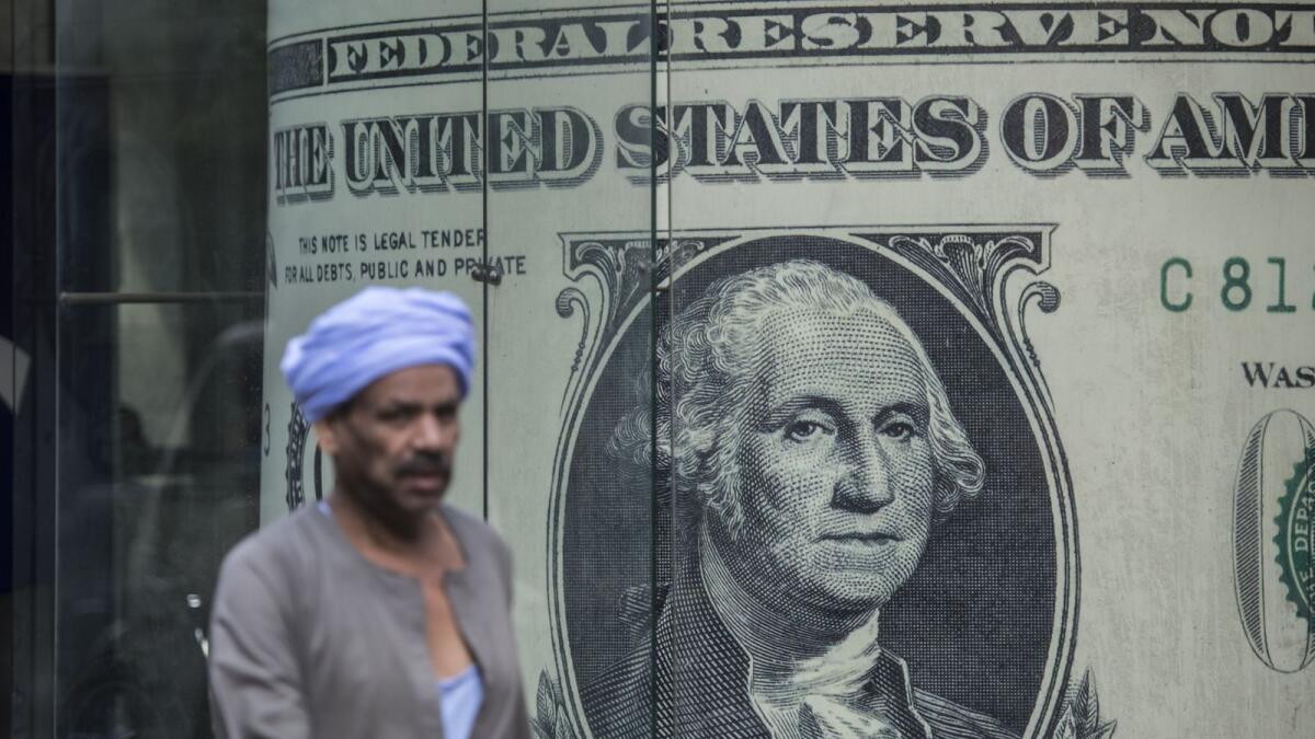 A man walks past a currency exchange shop displaying a giant US dollars banknote in downtown Cairo. On Wednesday the pound slid by about 6.8 per cent, its biggest one-day move since October when it was last allowed to drop sharply.