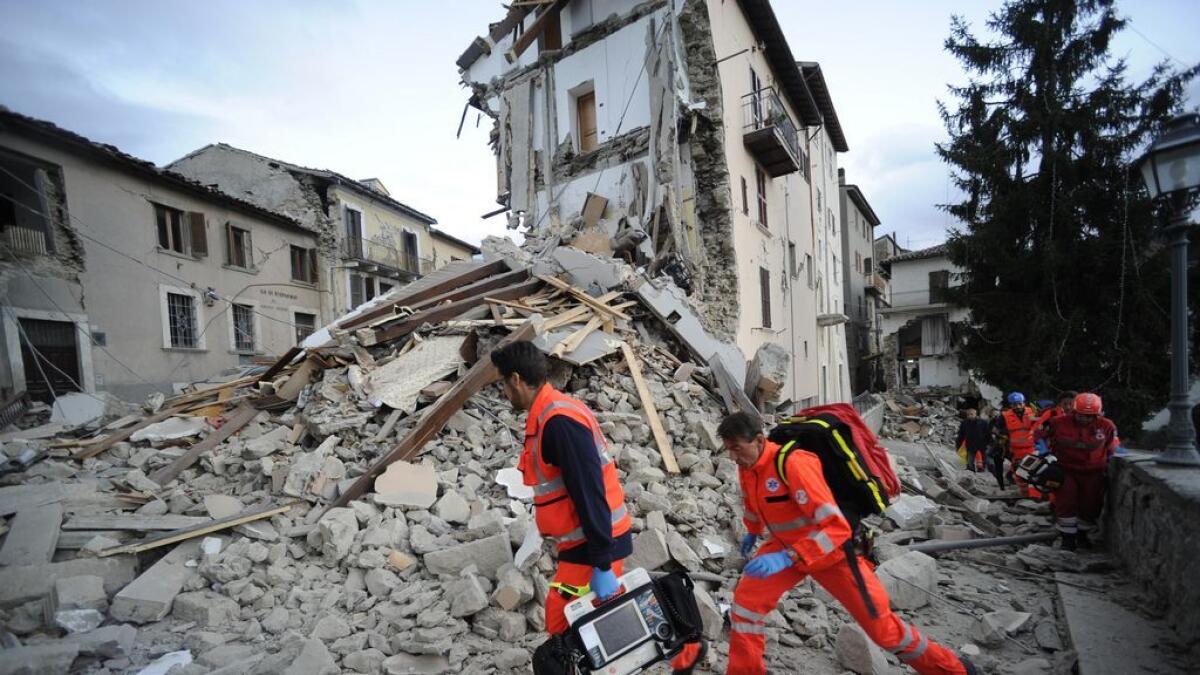 Rescuers search a crumbled building in Arcuata del Tronto, central Italy. AP