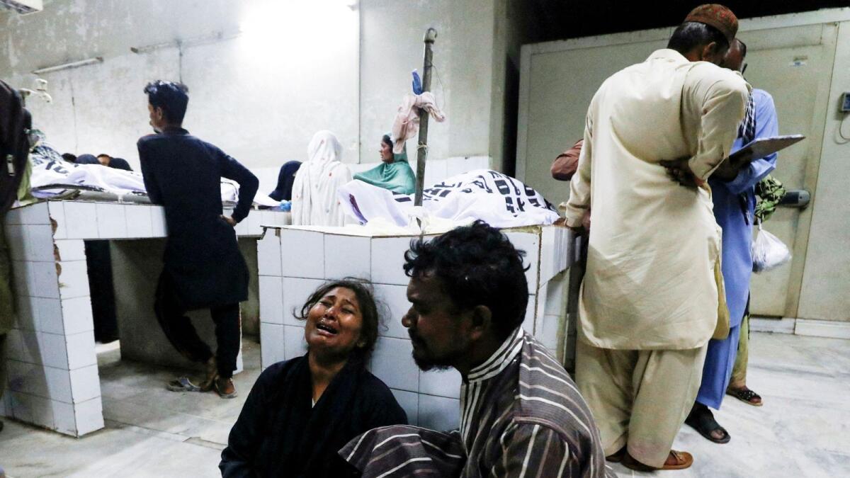 People mourn the death of a relative, who was killed along with others in a stampede during handout distribution, at a hospital morgue in Karachi. — Reuters