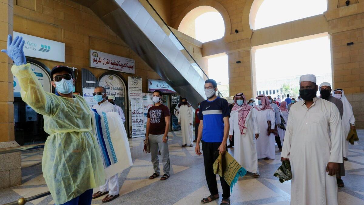 A security worker checks worshippers before they perform Friday prayers inside the Al Rajhi Mosque, Riyadh, Saudi Arabia, June 5, 2020.