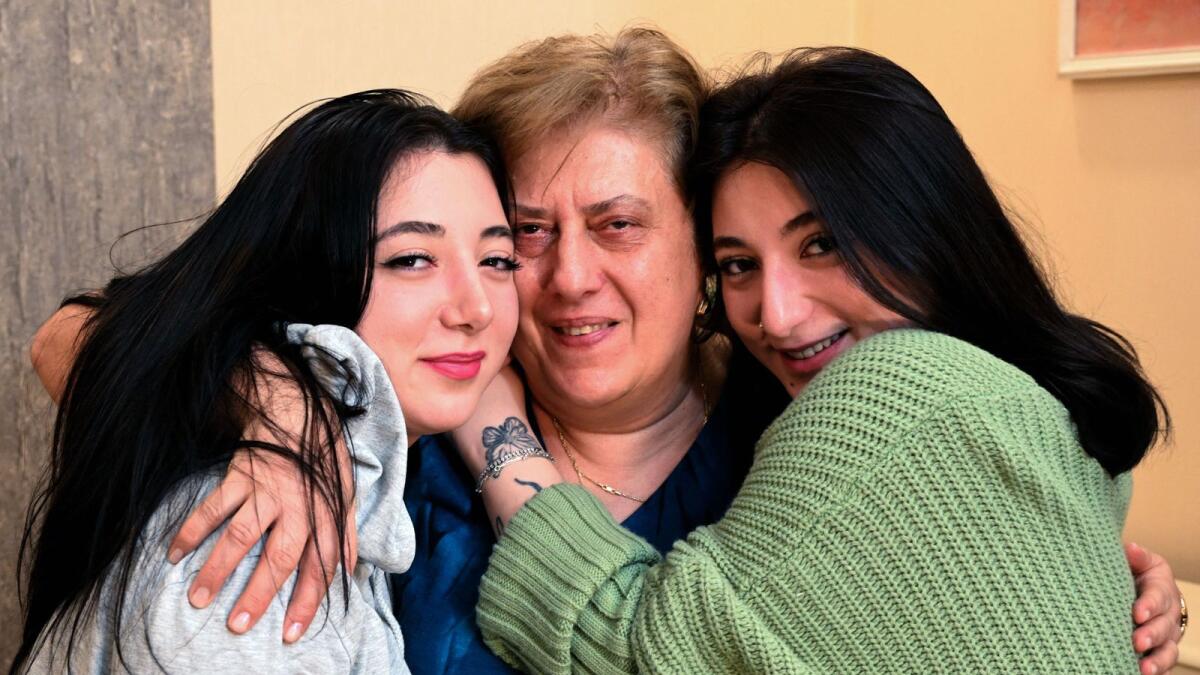 Georgian twin sisters Anna Panchulidze (L), an English student at university, and Elene Deisadze (R), a psychology student, and Elene's adoptive mother, Lia Korkotadze, pose during an interview in Tbilisi on March 23, 2024. — AFP