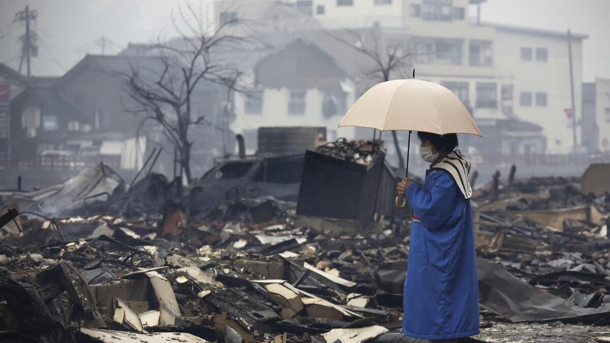 A woman looks at the burnt-out marketplace by a fire following earthquakes in Wajima. — AP