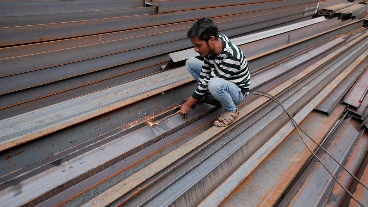 A worker cuts iron rods outside a workshop at an iron and steel market in an industrial area in New Delhi. — Reuters file