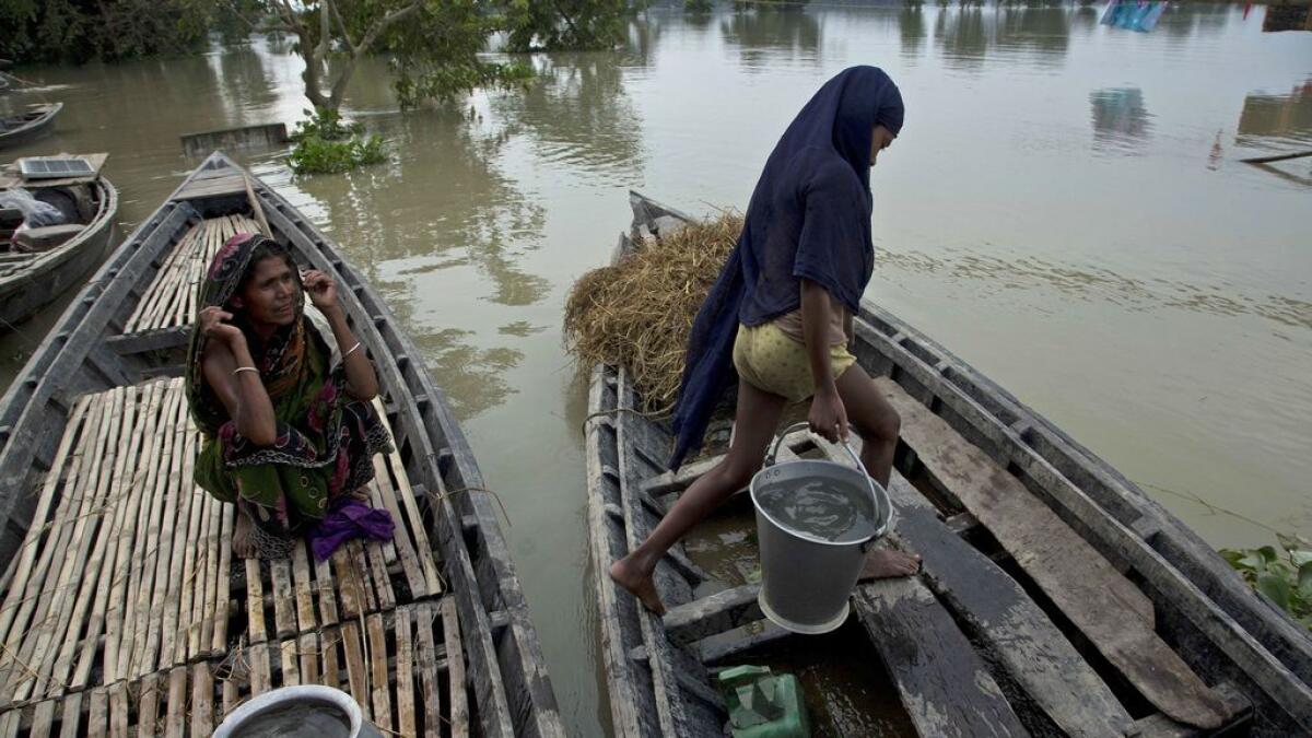 A girl carries drinking water into a boat to take to her flooded home at Sildubi village in Assam. 