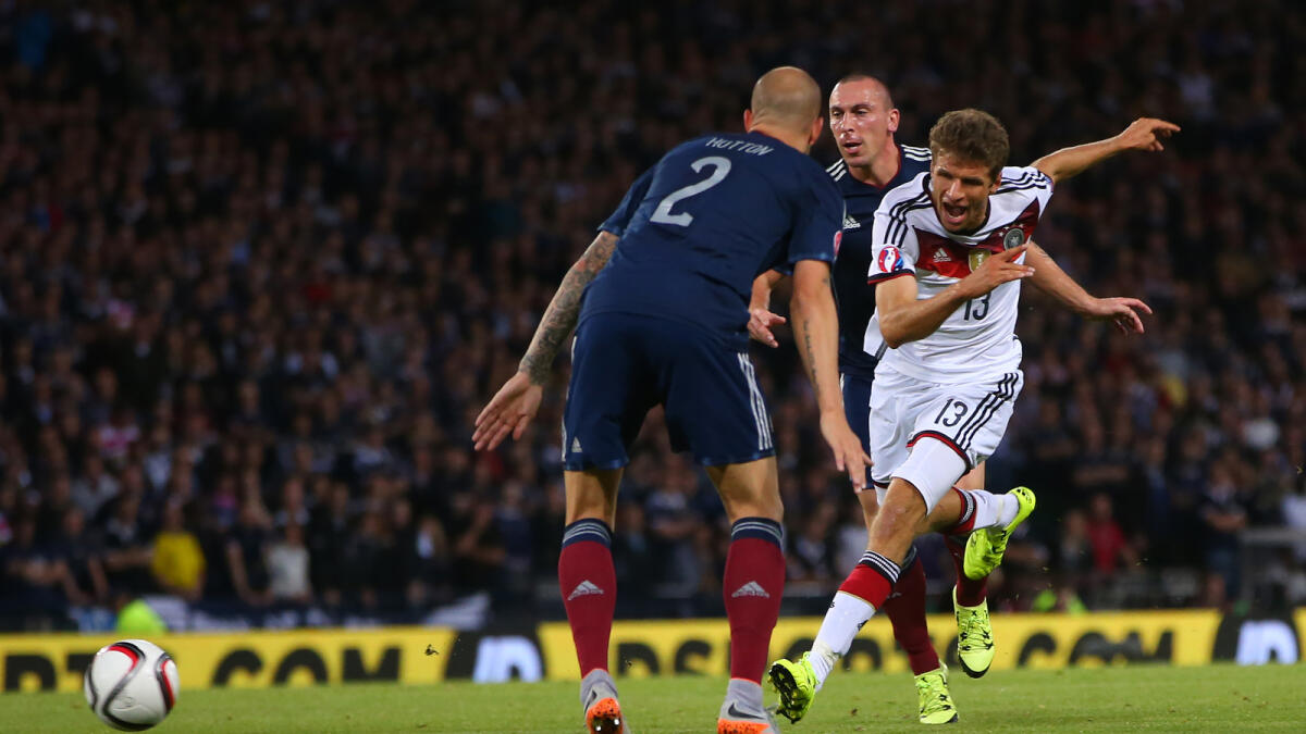 Germany’s  Thomas Muller (right) scores the opening goal of the Euro 2016 qualifying Group D football match against Scotland. 