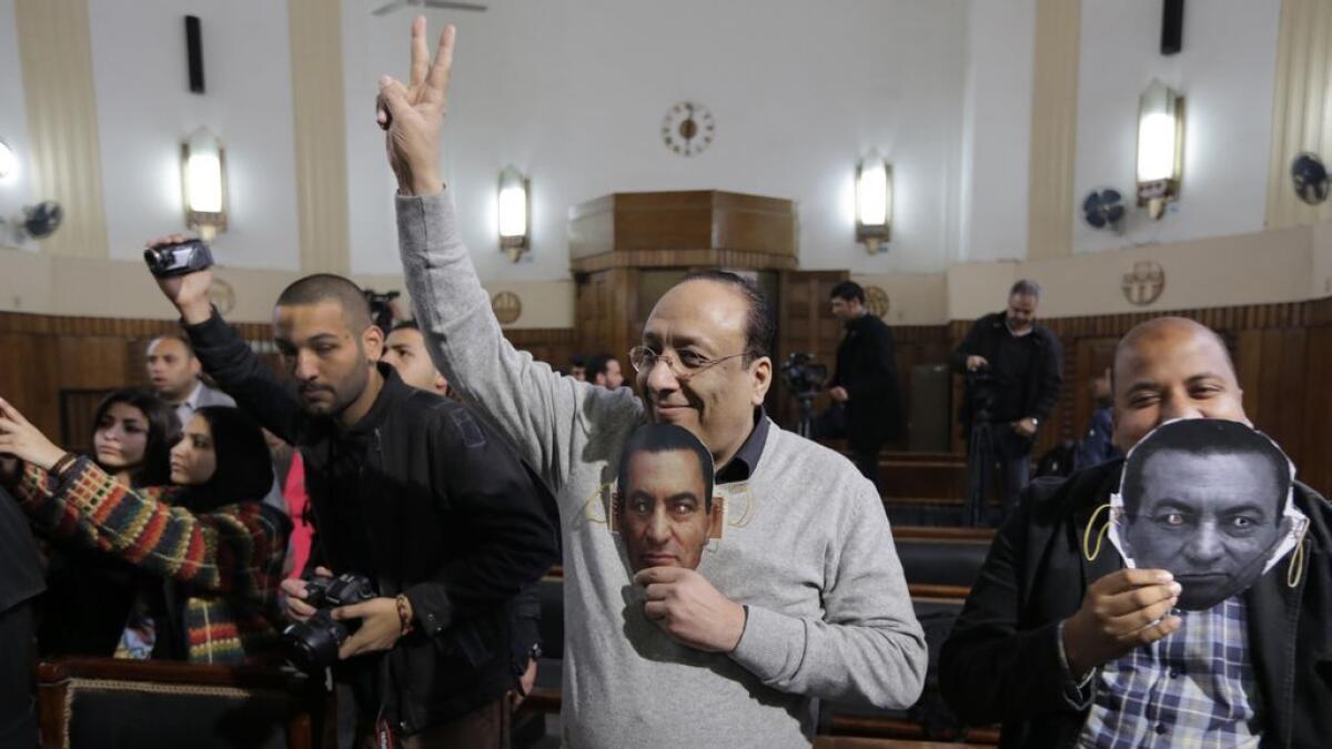 Supporter of Egypts ousted President Hosni Mubarak hold masks with Mubaraks face during a session at the Cairo High Court in Egypt. 