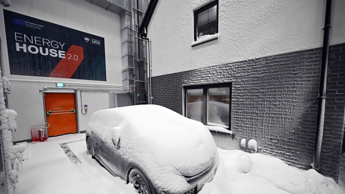 Simulated snow covers a car and the walls of one of two houses built to develop future heating solutions, at Energy House 2.0 at Salford University in Salford, north west England on January 24, 2023. — AFP