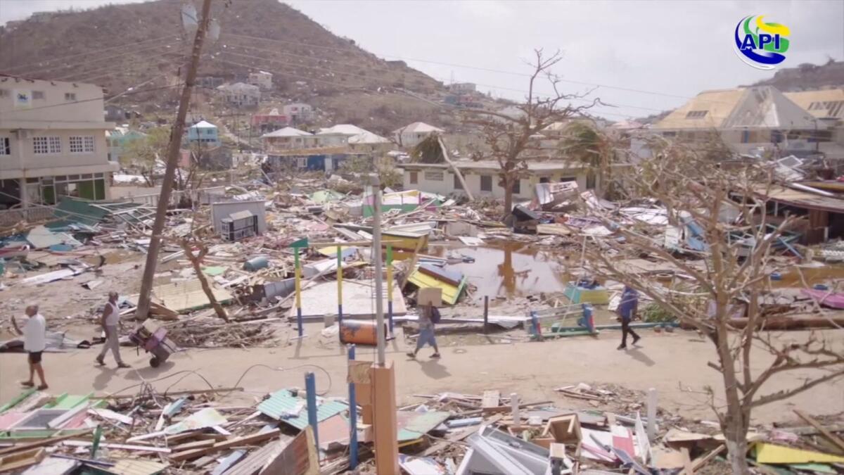 People walk amid damaged property following the passing of Hurricane Beryl, in Union Island, Saint Vincent and the Grenadines, in this screen grab taken from a handout video released on Tuesday. The Agency For Public Information St. Vincent and the Grenadines/Handout via REUTERS