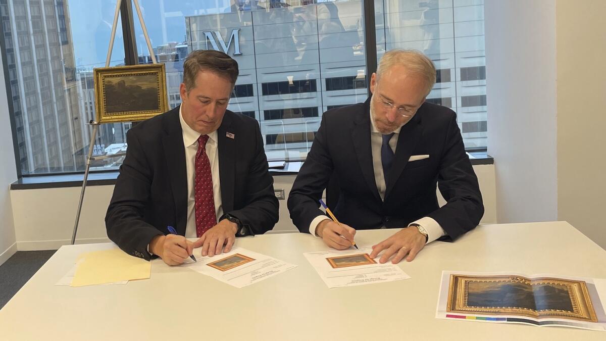 FBI Special Agent David White, left, and Bernd Ebert, a curator at the Alte Pinakothek in Munich, sign documents returning the painting in Chicago. — AFP