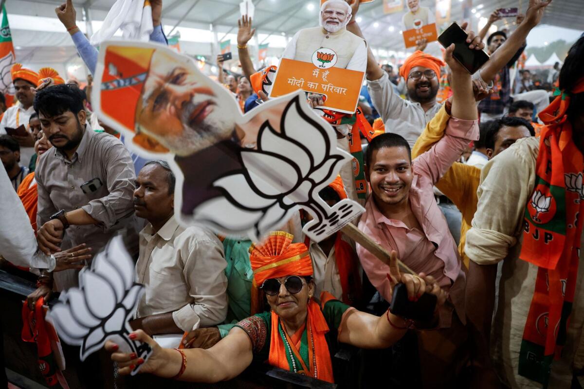 Bharatiya Janata Party's supporters hold cut-outs of India's Prime Minister Narendra Modi during his election campaign rally in New Delhi on Wednesday. — Reuters