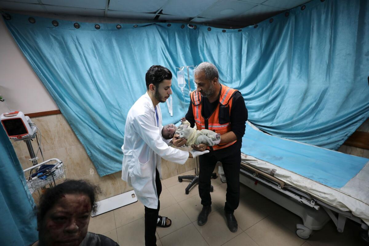 A Palestinian medic holds a child wounded in Israeli air strike on the Gaza Strip in Deir El Balah on Sunday.  — AP