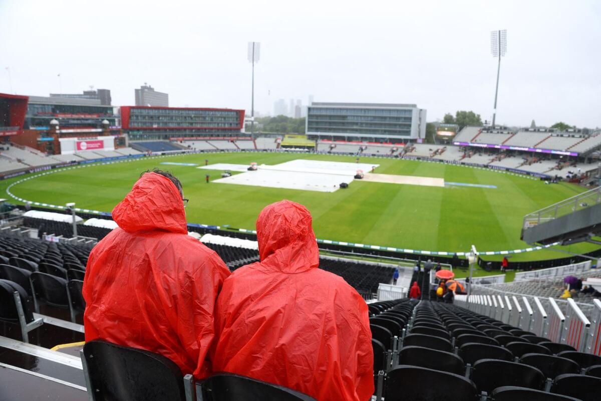 Spectators in ponchos look on at the covers on the field during the rain delayed day 4, 0 Reuters