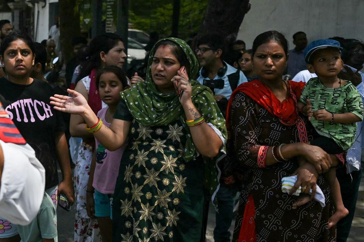 Relatives of infant victims wait to identify the missing children a day after fire blazed through a children's hospital in New Delhi. Photo: AFP
