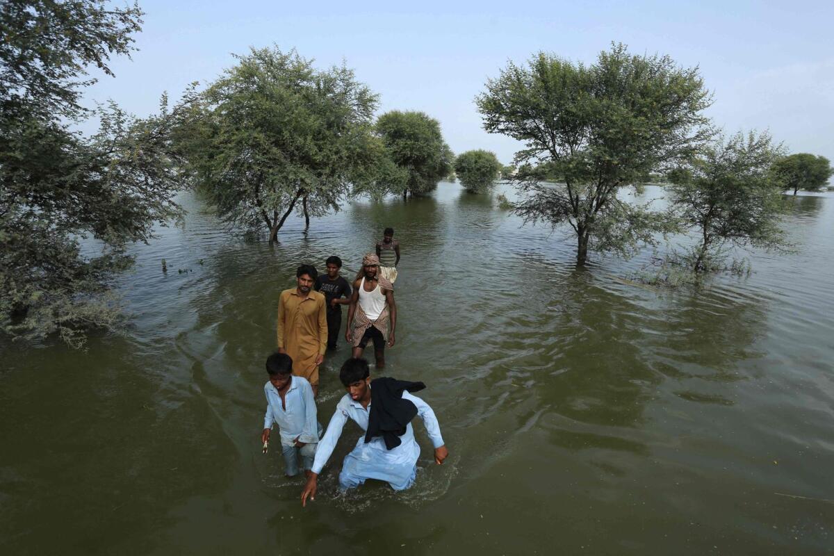 People wade a through flooded area of Burewala, a town of Vehari district in the Punjab province of Pakistan, on August 25, 2023.— AFP