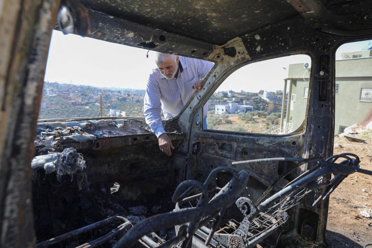 A Palestinian checks a car burned in Israeli settlers raid near Salfit in the Israeli-occupied West Bank on December 3, 2023. — Reuters