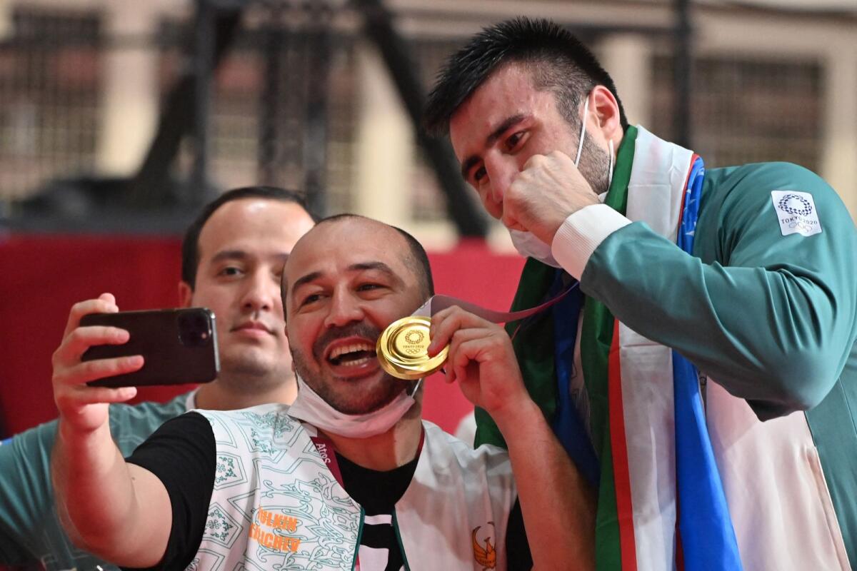 Gold medallist Bakhodir Jalolov of Uzbekistan poses with a fan after winning the gold medal in the men's super heavy (over 91kg) boxing category at the Tokyo 2020 Olympic Games. — AFP file