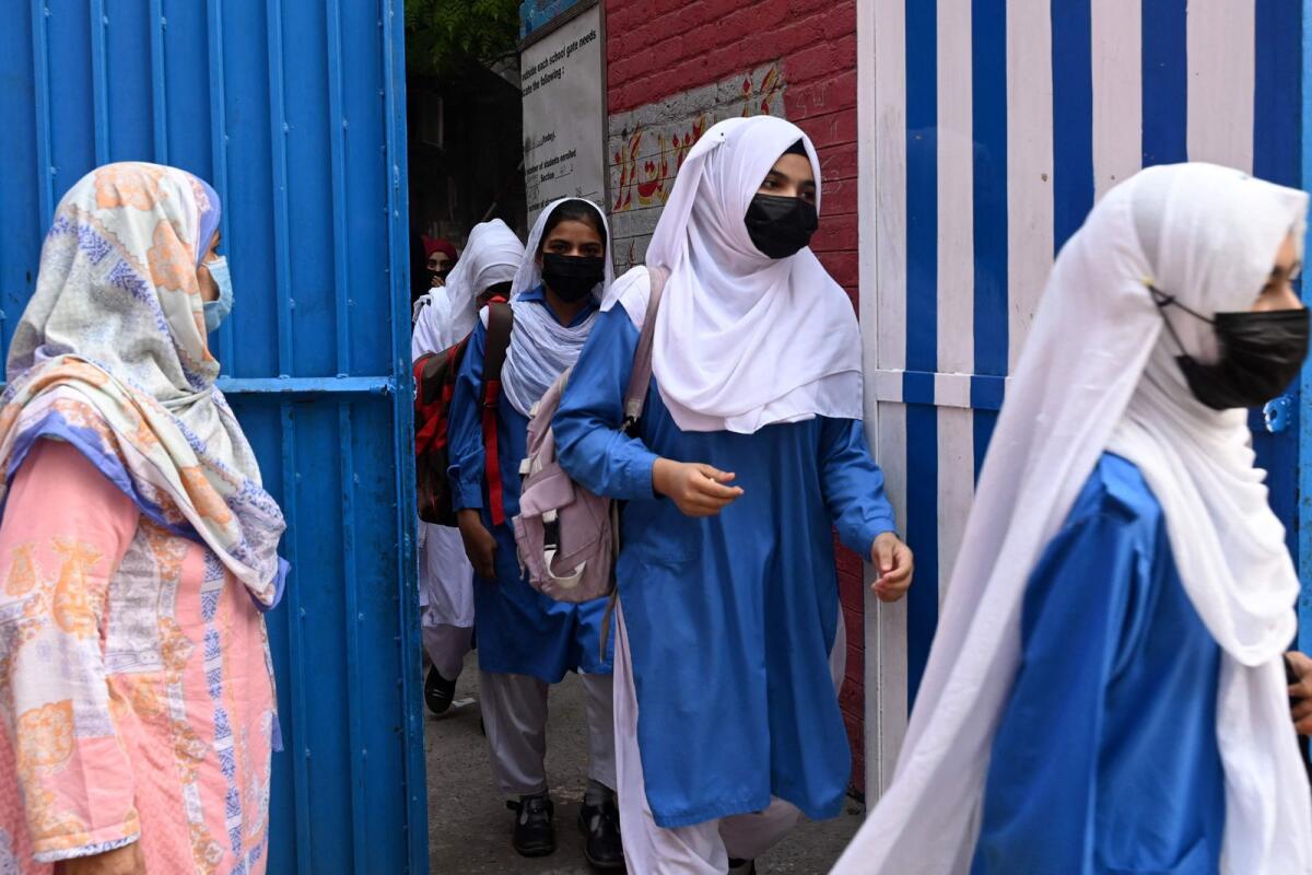 Students wearing facemasks arrive at a school in Lahore on Thursday. — AFP