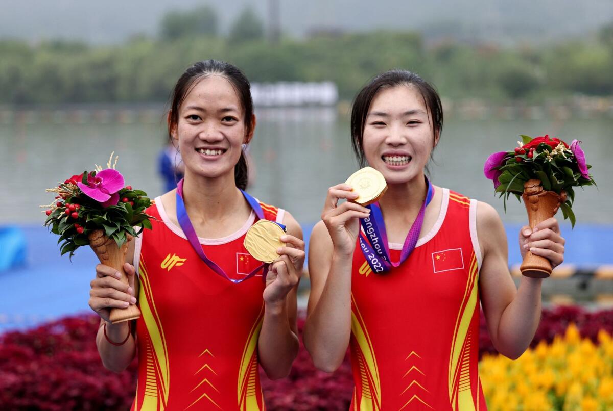 China's Jiaqi Zou and Xiuping Qiu celebrate on the podium after winning the the gold medal in the women's lightweight double sculls rowing. — Reuters