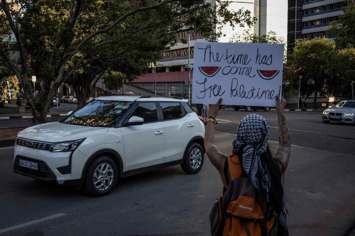 A Pro-Palestinian activist  holds a placard with images watermelon slices during a demonstration at the University of Witwatersrand  in Johannesburg on November 24, 2023.  — AFP