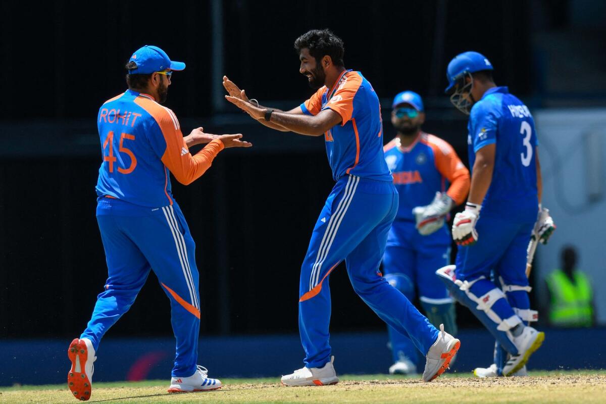 India's Jasprit Bumrah (centre) celebrates with Rohit Sharma after the dismissal of Afghanistan's Hazratullah Zazai (right). — AFP