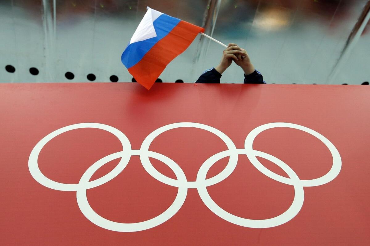 A Russian flag is held above the Olympic Rings at Adler Arena Skating Centre during the Winter Olympics in Sochi, Russia in 2014. — AP file