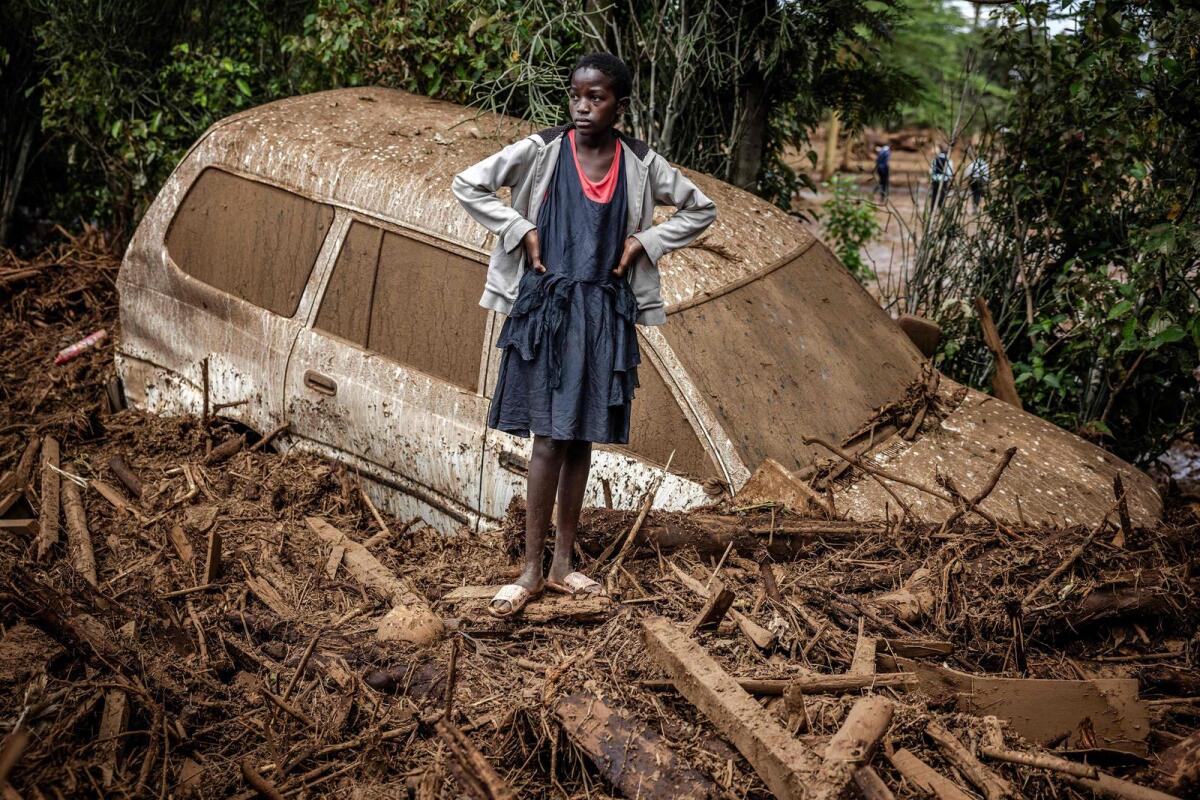 A girl looks on next to a damaged car buried in mud in an area heavily affected by torrential rains and flash floods in the village of Kamuchiri, near Mai Mahiu, on Monday. — AFP