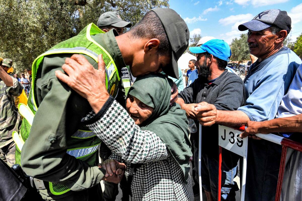 A member of Morocco's Auxiliary Forces embraces an elderly woman arriving to receive disaster relief aid from a distribution centre in the town of Amizmiz in Al Haouz province in the High Atlas mountains of central Morocco on September 12, 2023.  — AFP