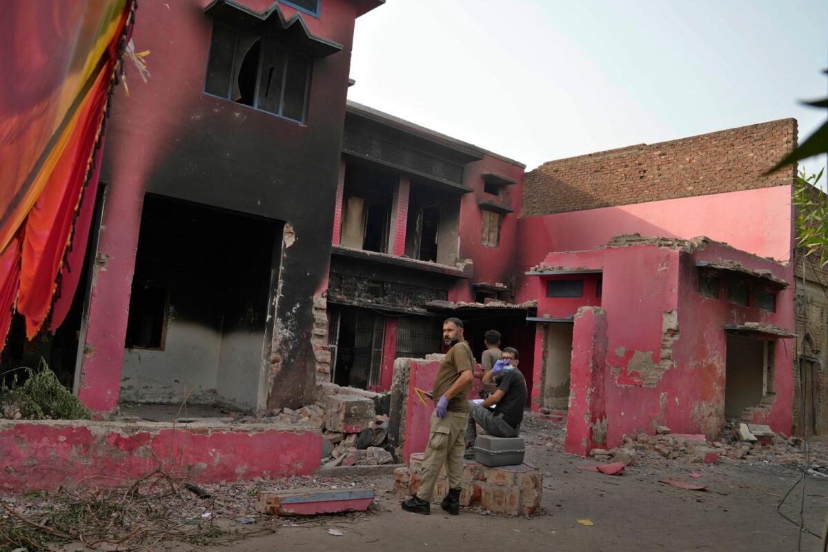 Police officers examine a church vandalized by angry Muslim mob in Jaranwala near Faisalabad, Pakistan, on Thursday. -- AP