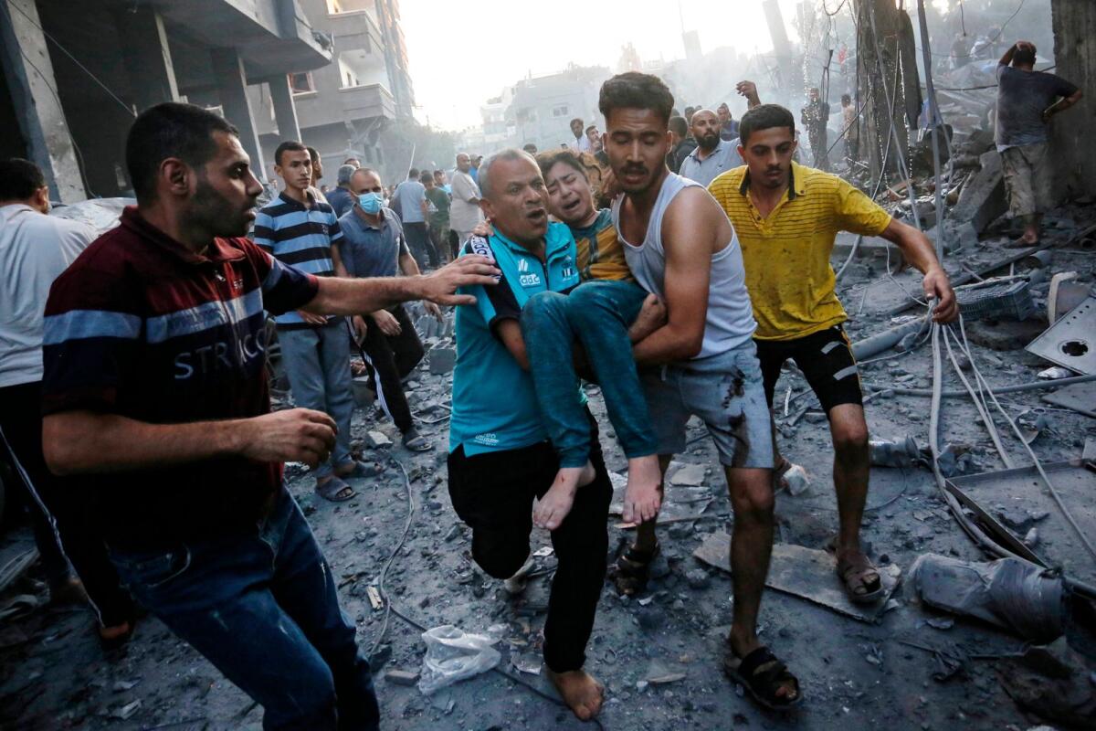 Men carry away an injured girl following an Israeli strike on the town of Deir Al-Balah in the central Gaza Strip on October 18 2023. Photo: AFP