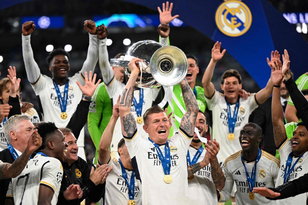 Real Madrid's German midfielder Toni Kroos (centre) and teammates lift the trophy to celebrate their victory at Wembley stadium in London. — AFP