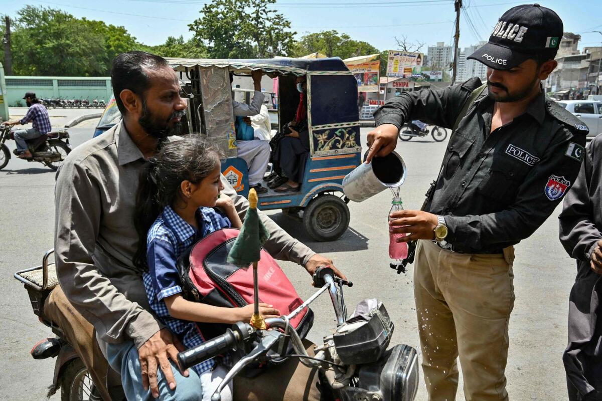 A policeman distribute cold drinks to bypassers near a 'heatwave relief camp' during a hot summer day in Karachi on May 23, 2024.  — AFP
