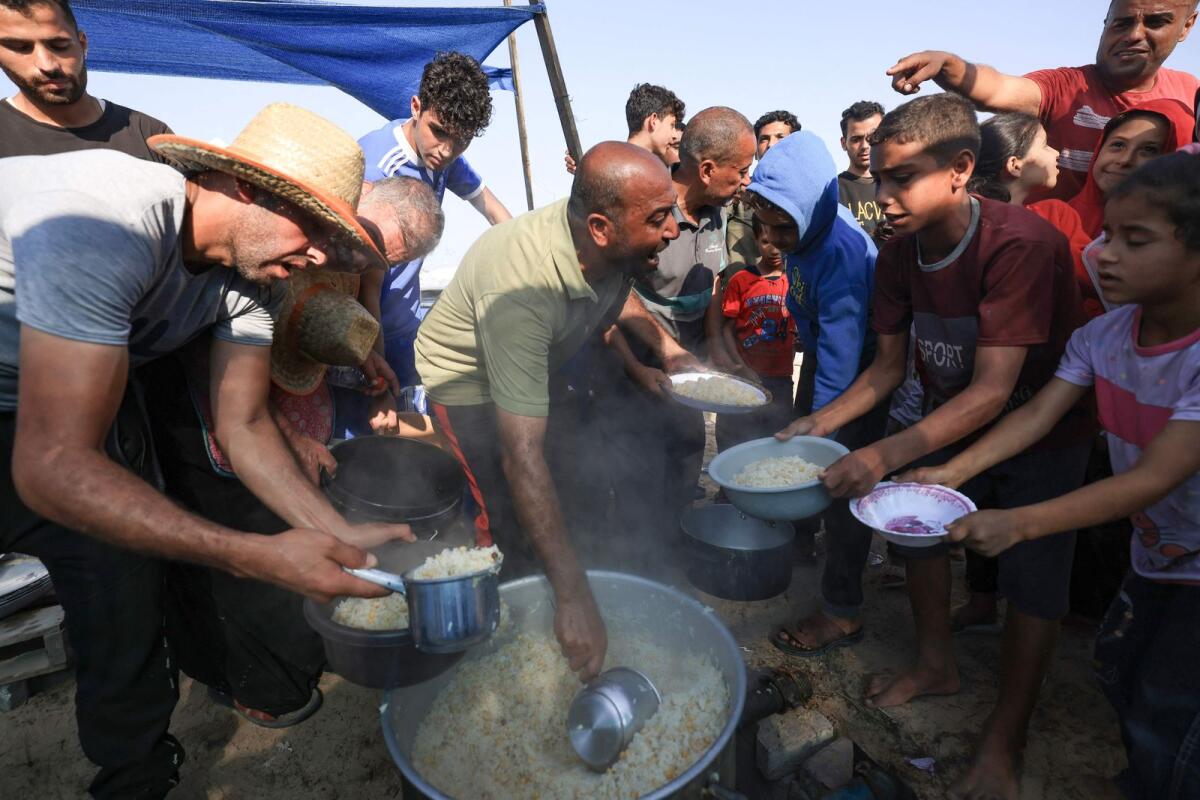 People distribute food to people at a makeshift camp for displaced people in Khan Yunis in the southern Gaza Strip on October 25, 2023, as battles between Israel and the Palestinian Hamas movement continue. Photo: AFP