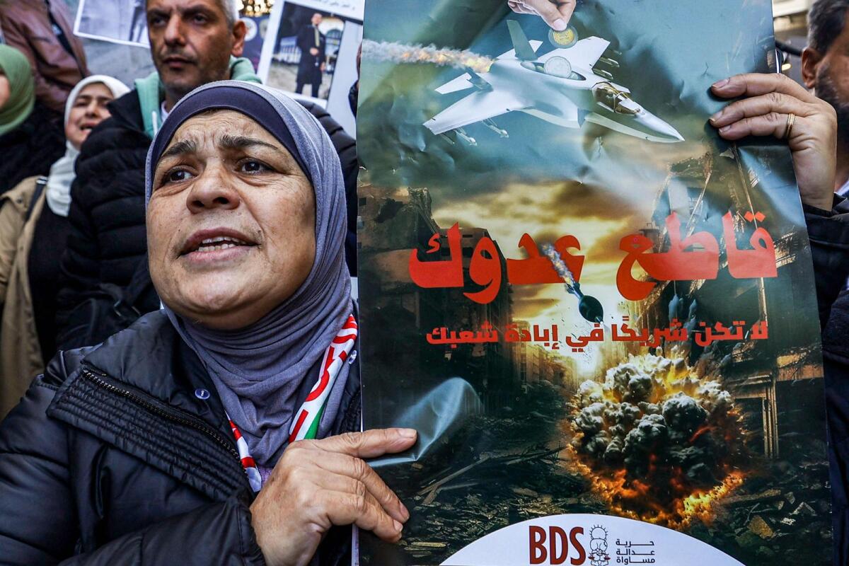 A woman holds a sign calling for the boycott of Israeli products during a demonstration in Ramallah in the occupied West Bank on December 26, 2023, as part of a wider campaign urging Palestinians to boycott Israeli products and buy locally made goods.— AFP file