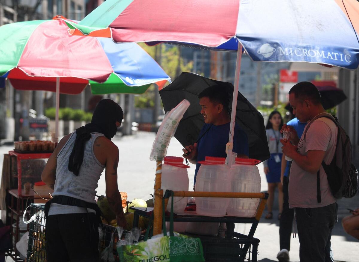 People buy coconut water to cool themselves along a road in Manila on April 24, 2024, as extreme heat affected the country. Photo: AFP