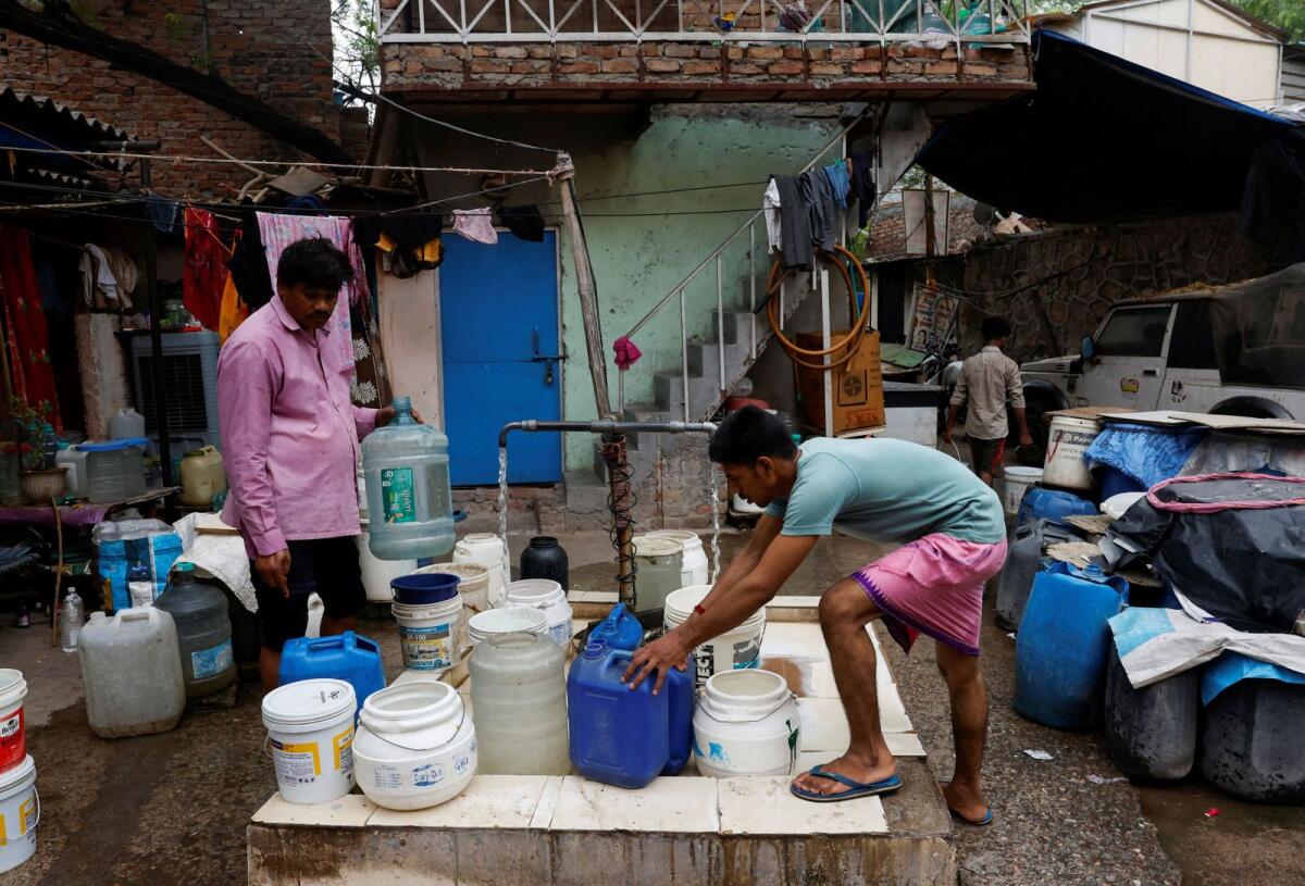 Residents fill their containers from a tap that dispenses water twice a day at a slum in New Delhi, India, on June 27, 2024. Reuters
