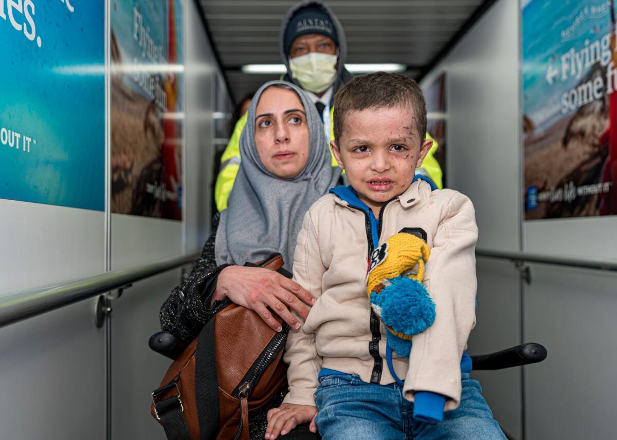 Four-year-old Omar Abu Kuwaik and his aunt Maha Abu Kuwaik, both from Gaza, are escorted through John F. Kennedy International Airport after departing a flight from Egypt on Wednesday, on Jan. 17, 2024, in New York. — AP