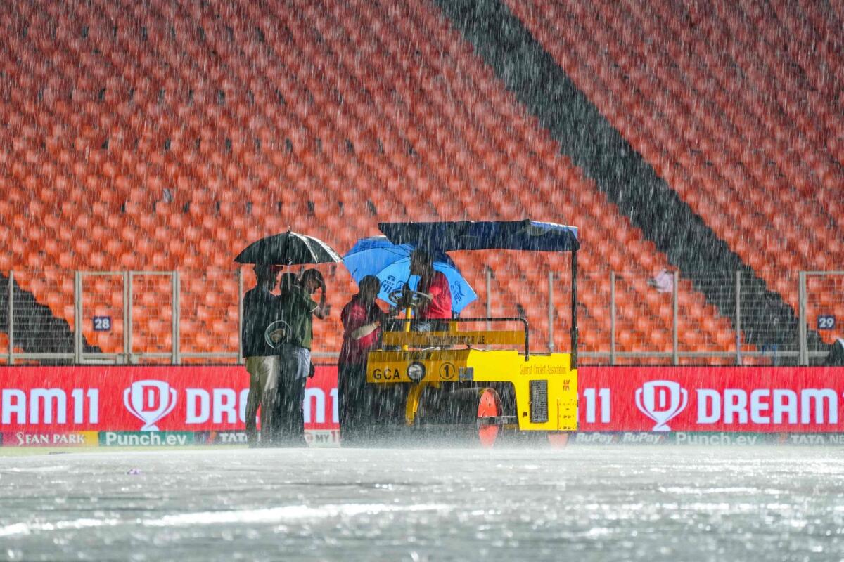 Ground staff take shelter under umbrellas at the Narendra Modi Stadium in Ahmedabad. — AFP