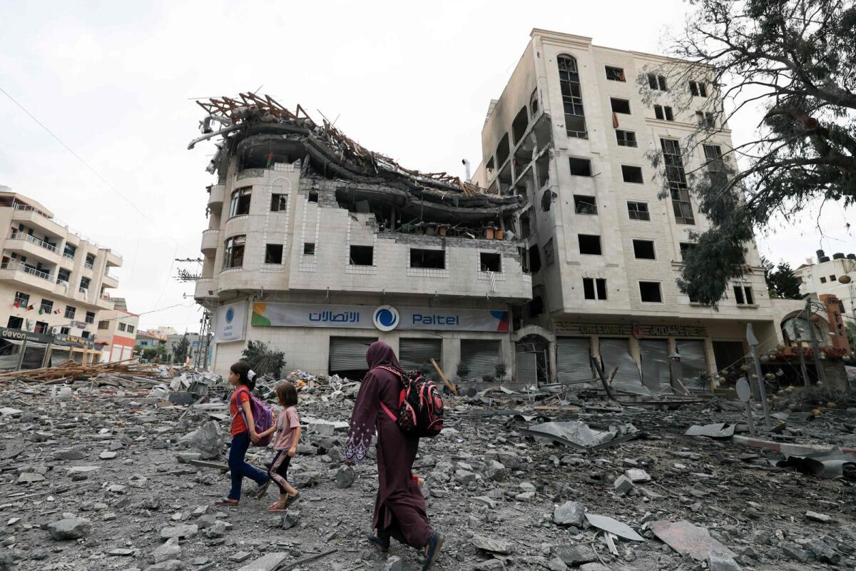 Palestinians walk through debris amid massive destruction from Israeli airstrikes in Gaza City's Al Rimal district, on Tuesday. — AFP