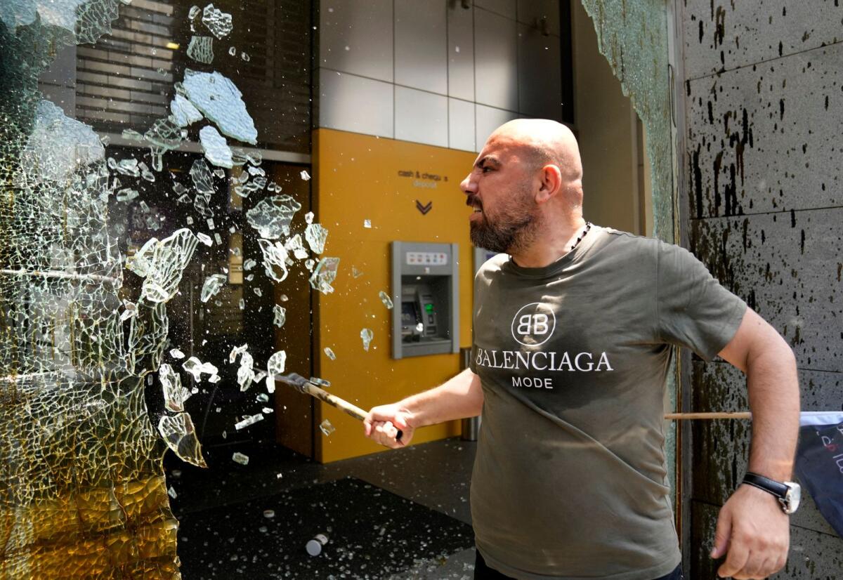 A man smashes windows at Byblos Bank during a protest demanding the release of depositors' trapped savings, in Beirut, Lebanon, Thursday, June 15, 2023. -- AP file