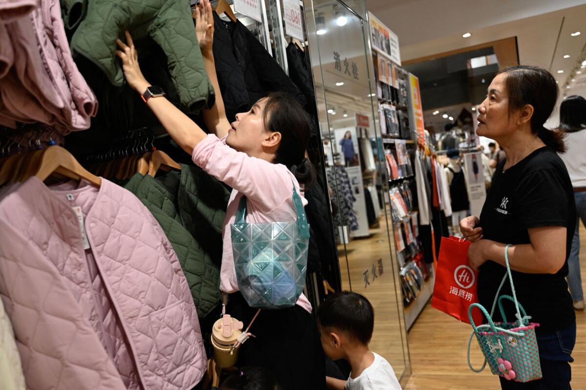Shoppers browse through clothing for sale at a mall in Beijing on September 17, 2023. – AFP