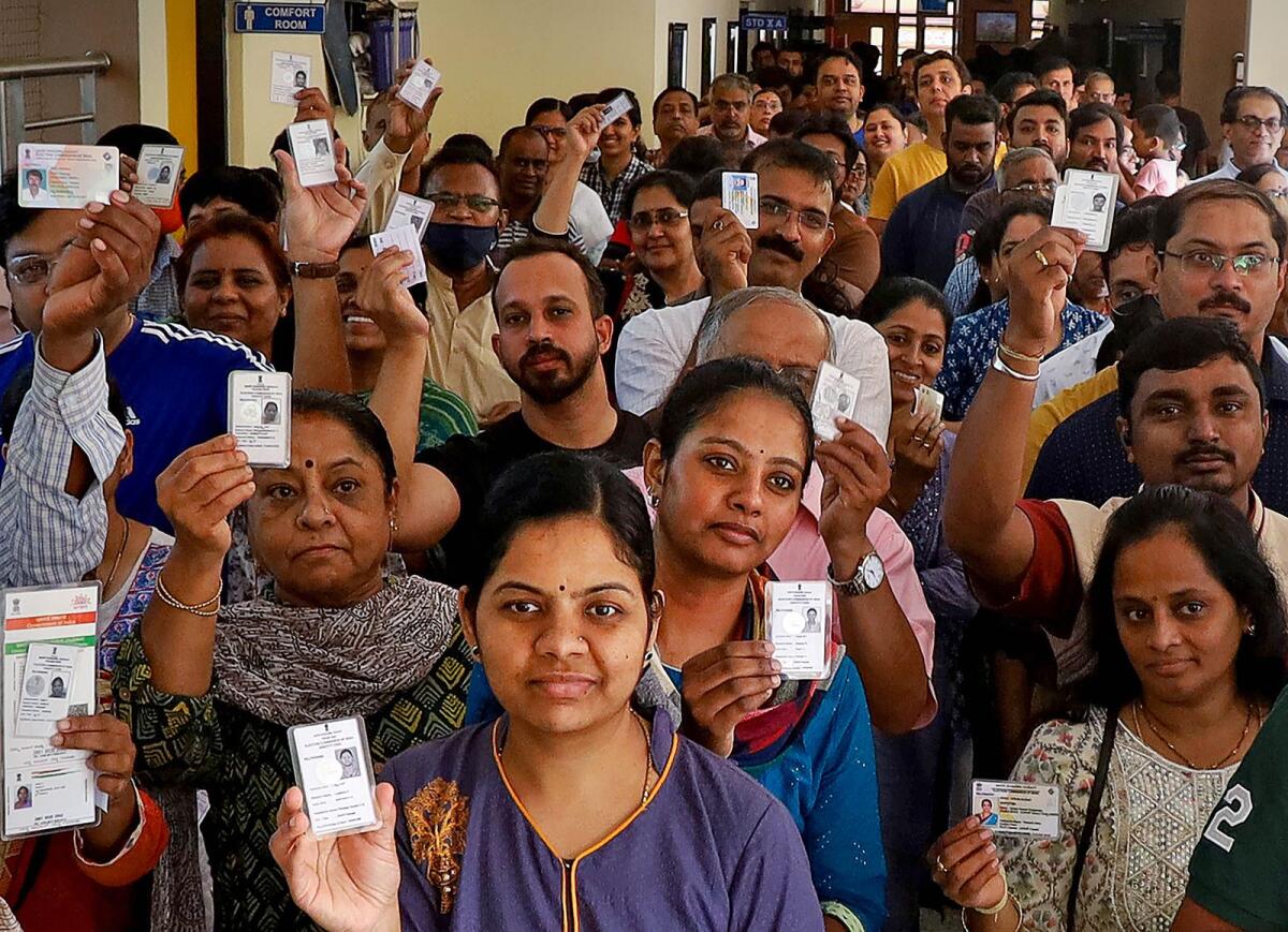 Voters pose for a photo showing their identification cards while waiting to cast their votes for the Karnataka Assembly elections in Bengaluru on Wednesday. Photo: PTI