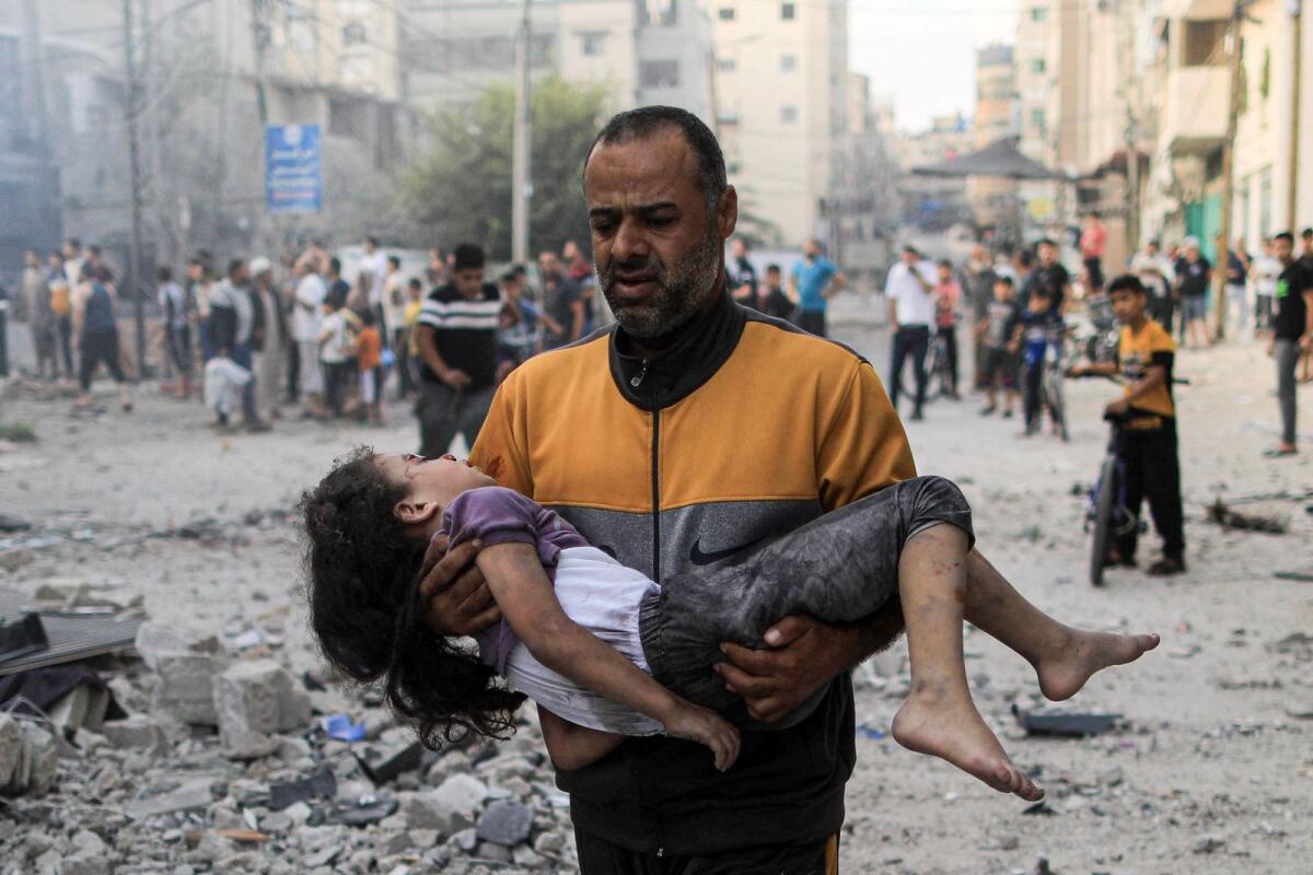 A Palestinian man carries an injured a girl following an Israeli strike, in Khan Yunis in the southern Gaza Strip.  — AP