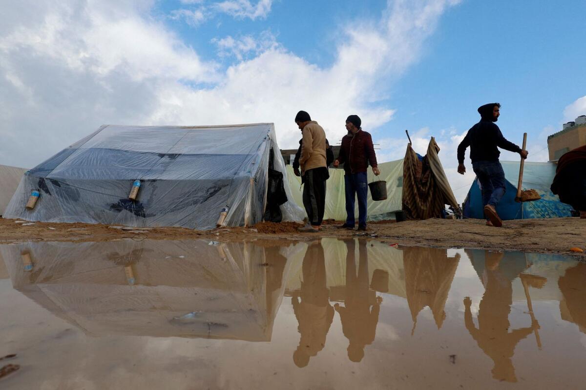 Displaced Palestinians walk next to tents following heavy rains at tent camps. Photo: Reuters