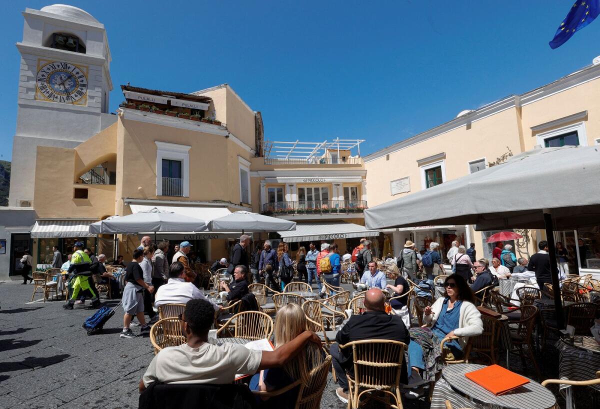 People sit at the tables outside restaurants and cafes on Capri Island, Italy, on April 18, 2024. R— Reuters