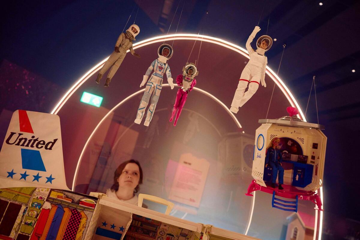 A gallery assistant looks at a Barbie doll taken to space by European Space Agency (ESA) astronaut and Europe's first female commander of the International Space Station Samantha Cristoforetti (top R) during the 'Barbie: The Exhibition' photocall at The Design Museum in London on July 1, 2024. — AFP