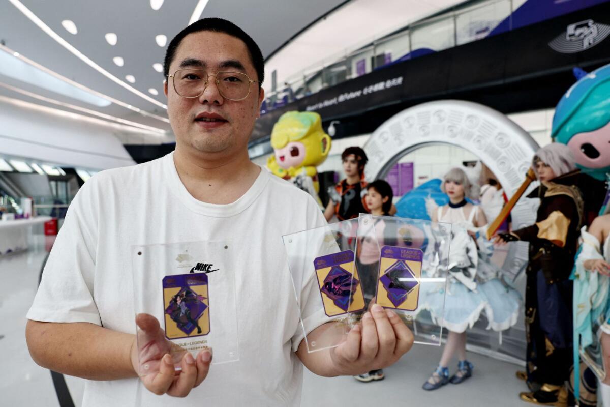 A fan poses with League of Legends cards outside the venue. — Reuters
